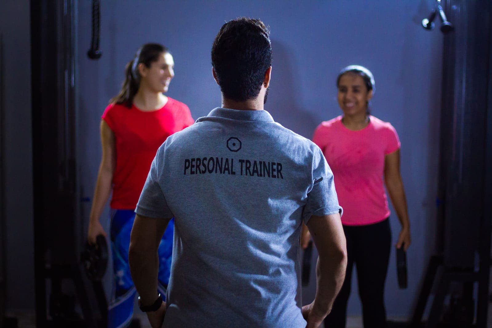A personal trainer meeting two members on the gym floor